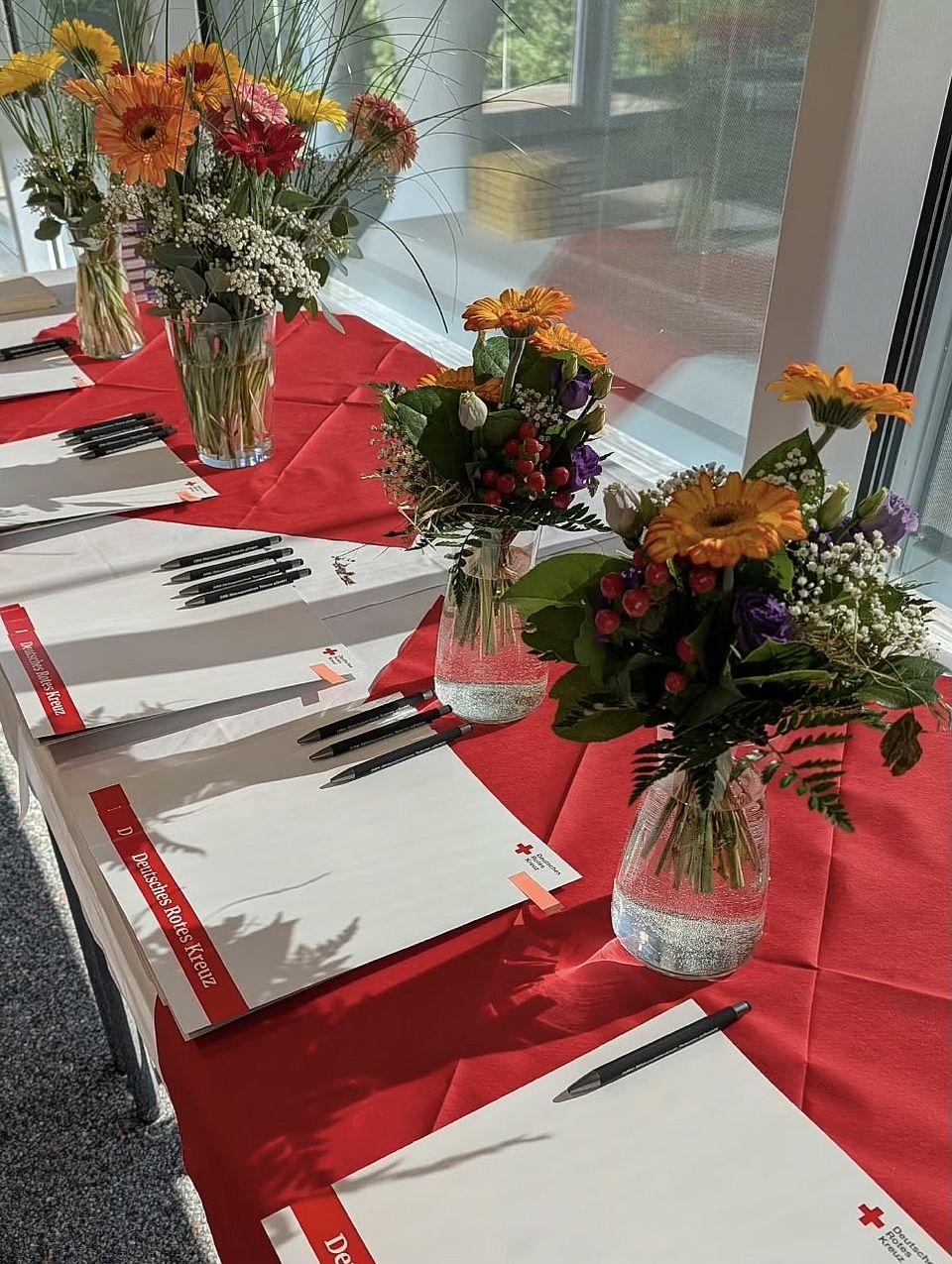 Ein in rot-weiß eingedeckter Tisch mit Blumen und Zeugnismappen.